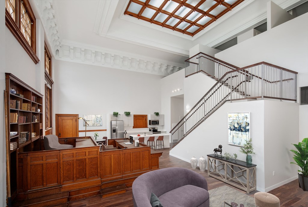 a living room with white walls and a staircase in the middle