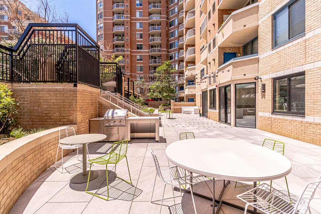 a patio with tables and chairs and a grill