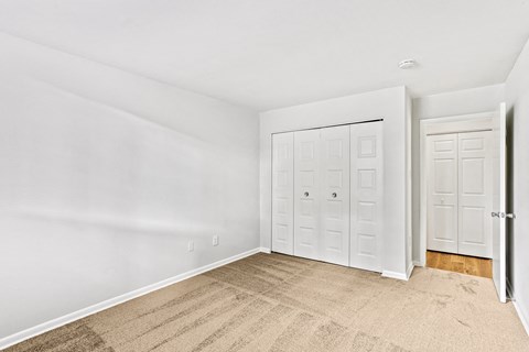 a bedroom with two closets and a carpeted floor