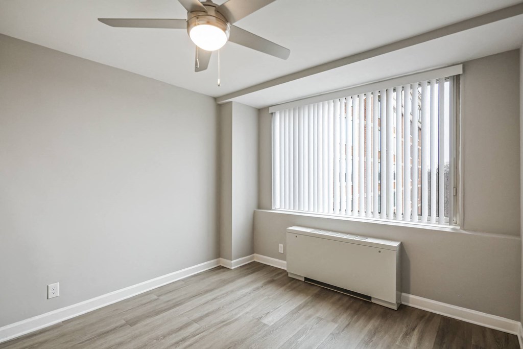 an empty living room with a large window and a ceiling fan