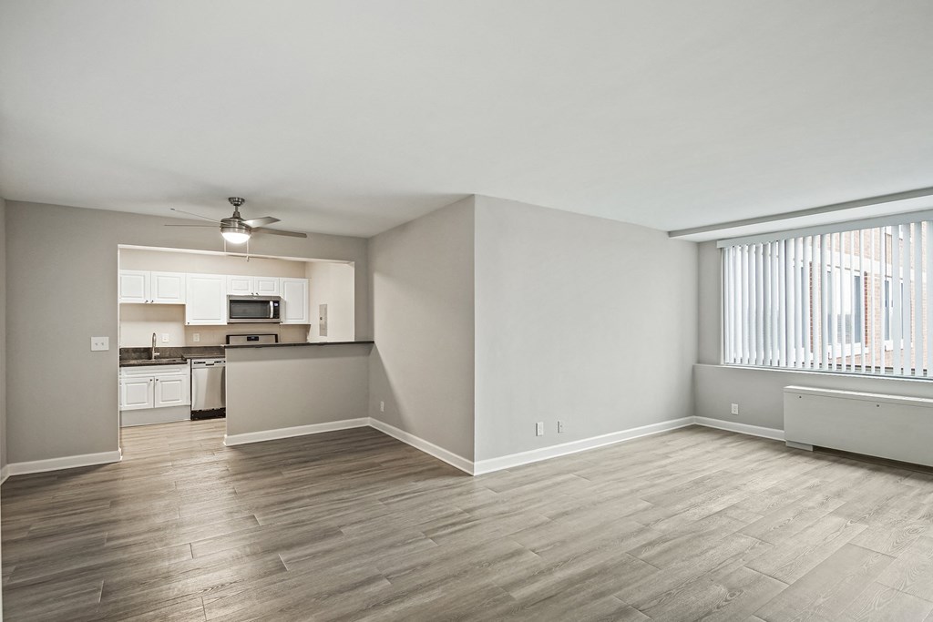 an empty living room and kitchen with wood flooring and a window