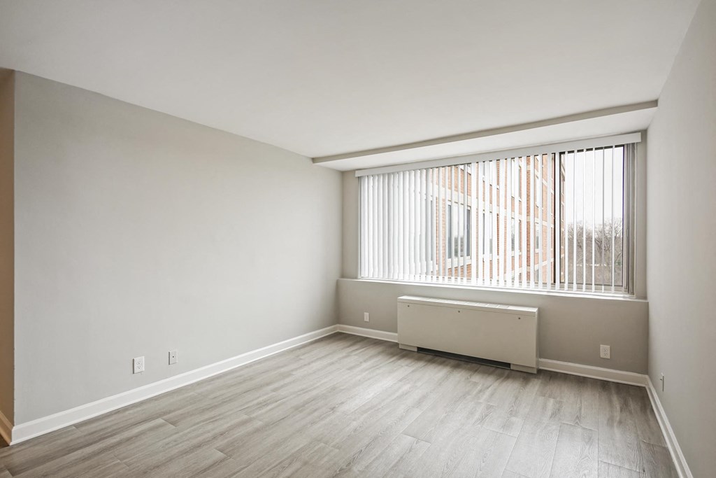 an empty living room with a large window and wood flooring
