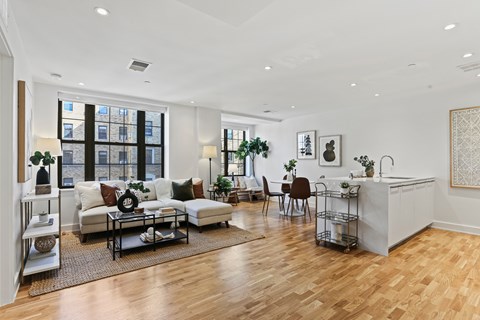 A living room with a white sofa set and a wooden floor.