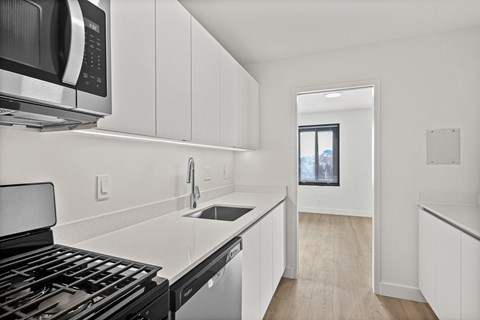 A modern kitchen with white cabinets and a black stove top oven.