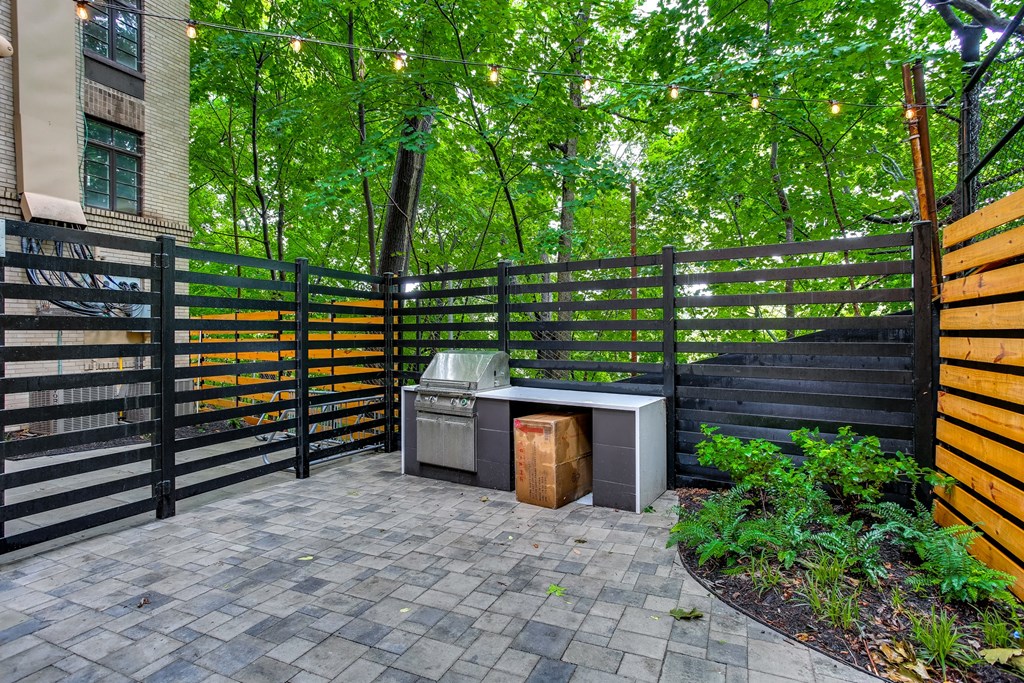 A black gate with a yellow stripe is in front of a green tree.