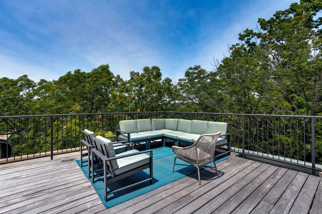 A wooden deck with a table and chairs overlooking a forest.