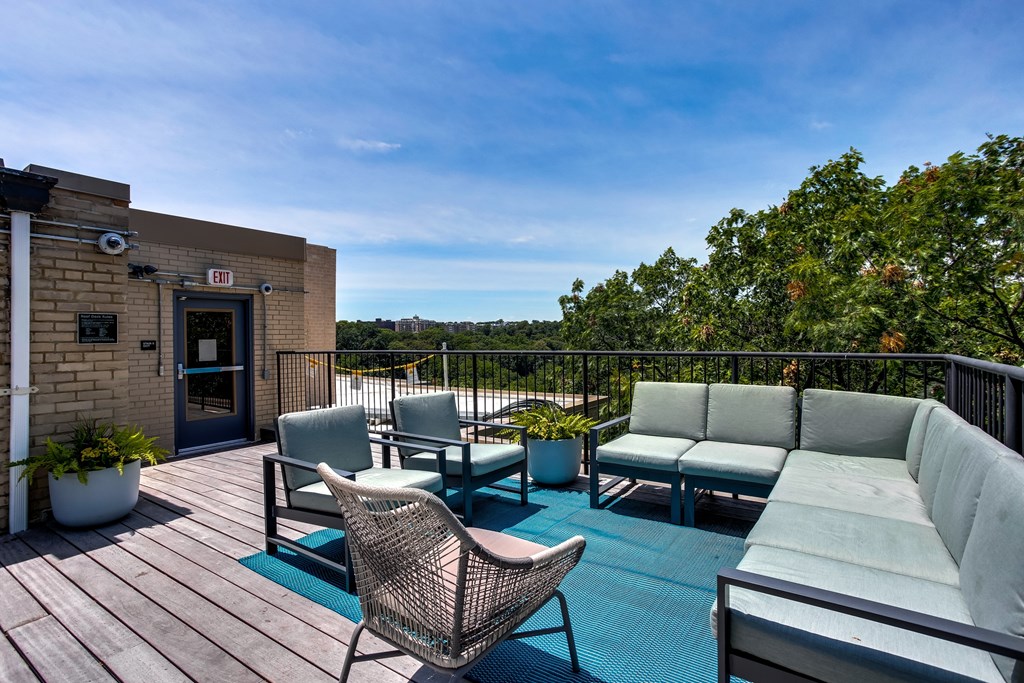 A patio with a couch, chairs, and a table with a view of the trees.