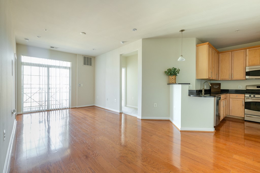 an empty living room and kitchen with wood flooring