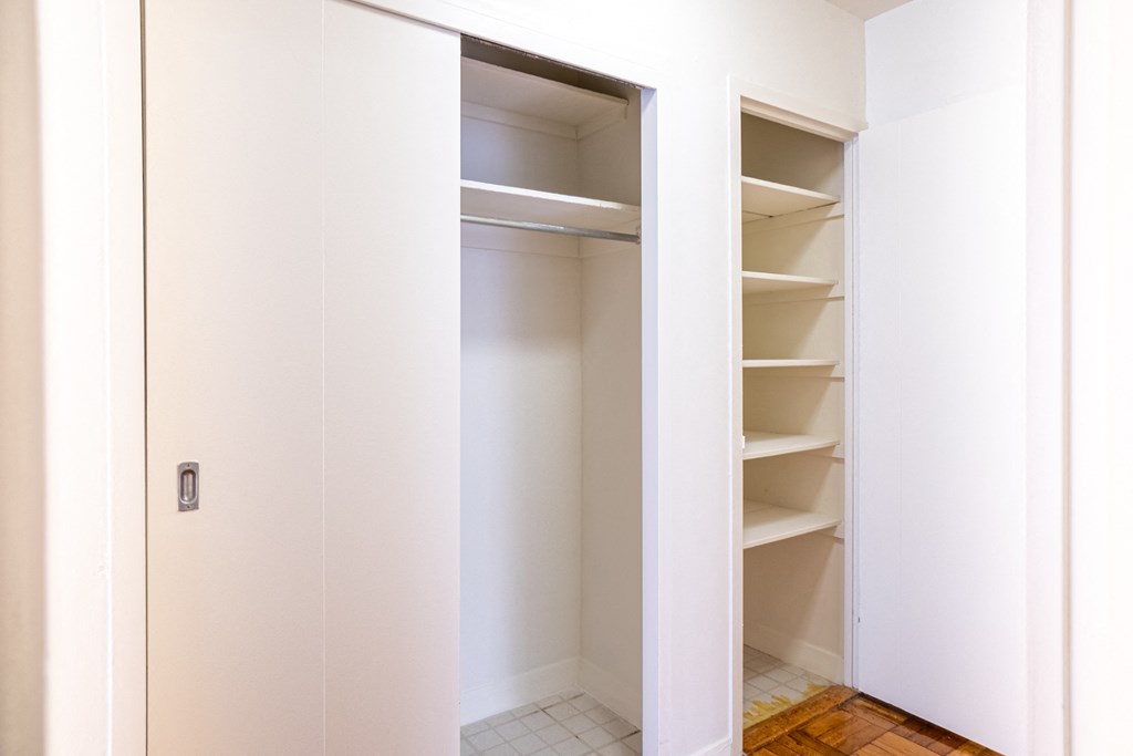 a walk in closet in a home with white walls and shelves