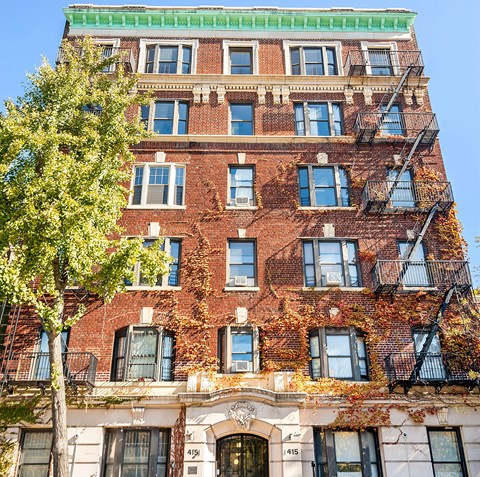 A red brick building with a tree in front of it.