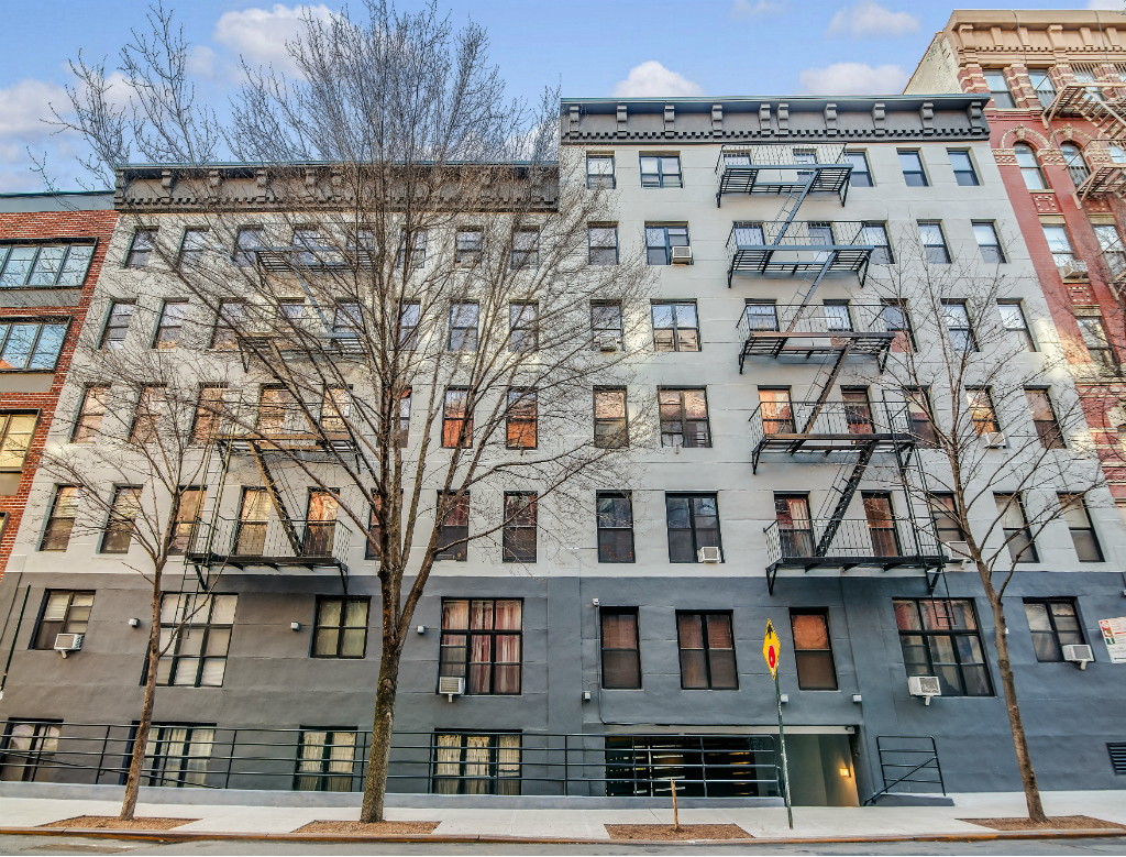 A grey building with a tree in front of it.