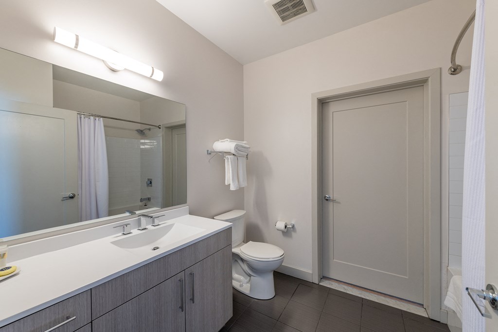 a bathroom with a toilet sink and mirror and a shower