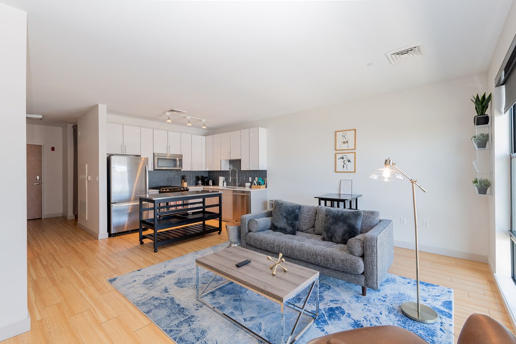 a living room with a couch and a coffee table and a kitchen in the background