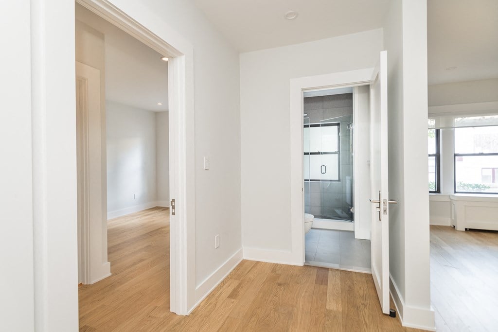 a living room and bedroom with white walls and wood flooring