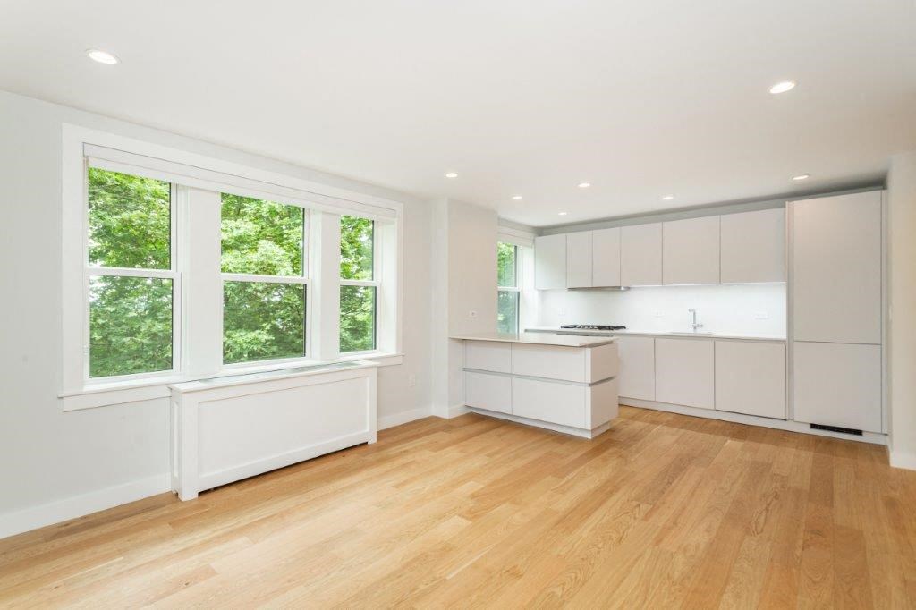 an empty kitchen with white cabinets and a large window