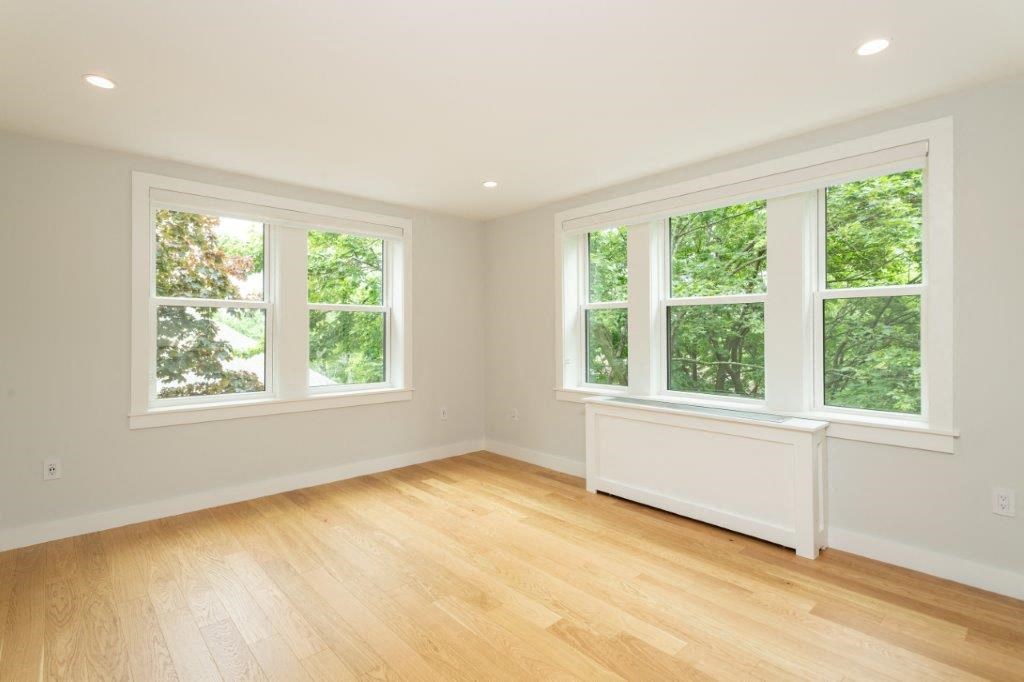 a living room with a hard wood floor and three windows