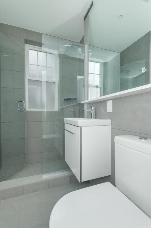 A white toilet sits next to a white cabinet in a bathroom.