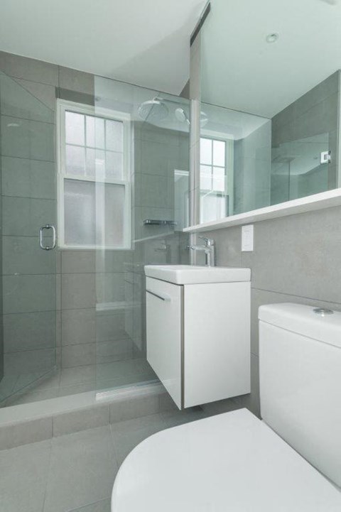 A white toilet sits next to a white cabinet in a bathroom.