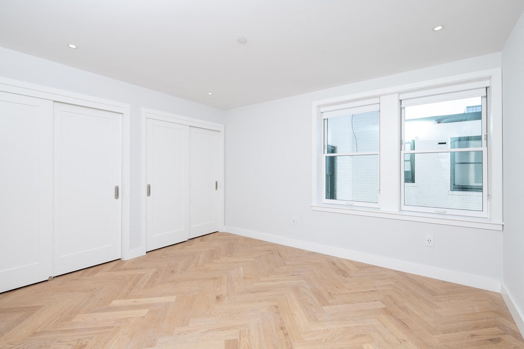 a bedroom with hardwood floors and white walls