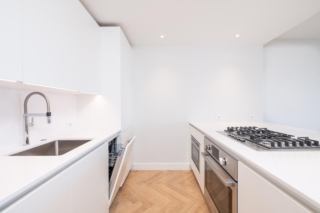 a kitchen with white cabinets and a wooden floor