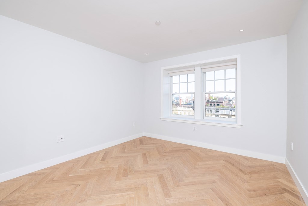 a bedroom with a wooden floor and a window
