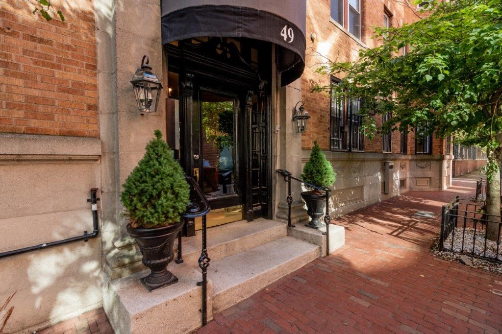 the front entrance of a building with a black door and potted plants
