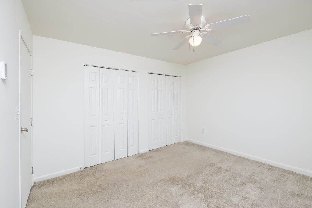 a bedroom with two closets and a ceiling fan