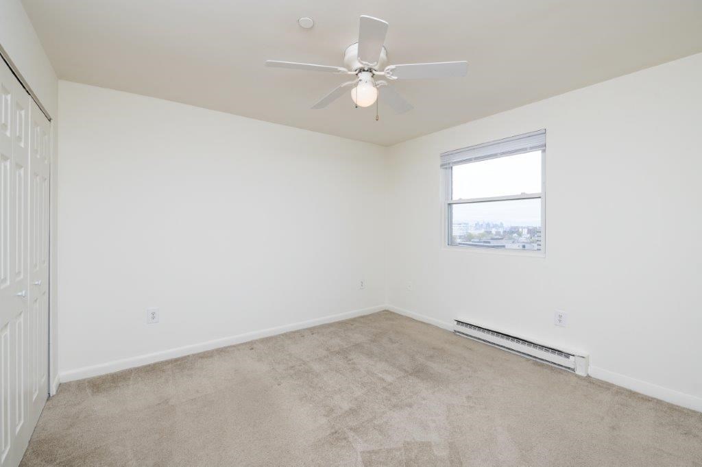 an empty room with a ceiling fan and a window