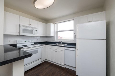 a white kitchen with white appliances and black counter tops