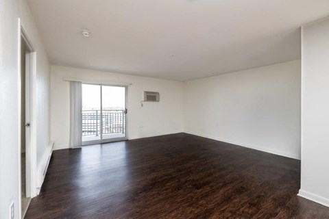 an empty living room with wood flooring and a balcony