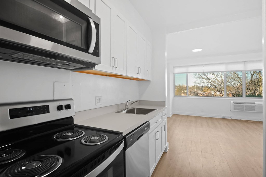 a kitchen with white cabinets and black appliances and a window