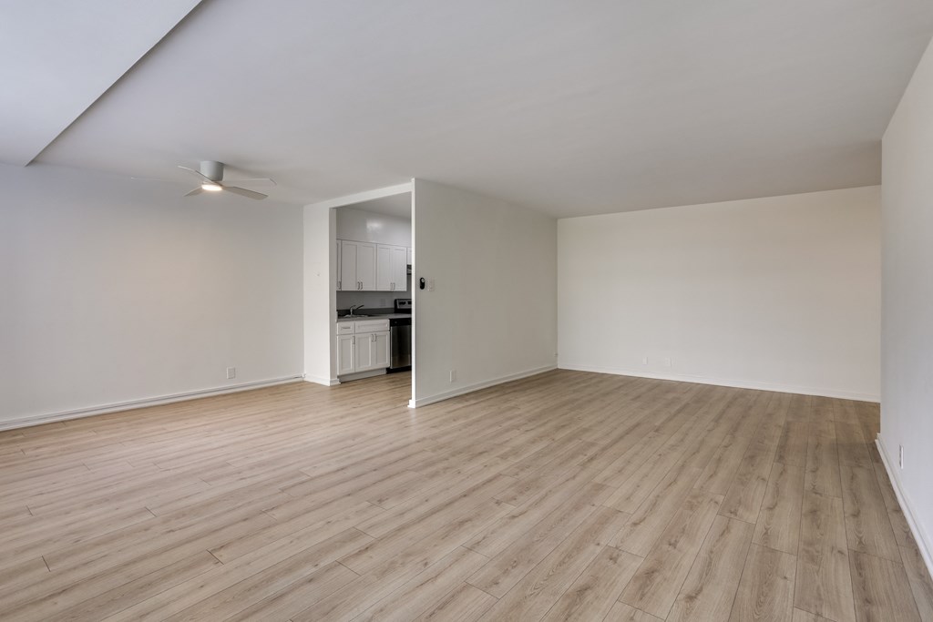 an empty living room with wood floors and white walls