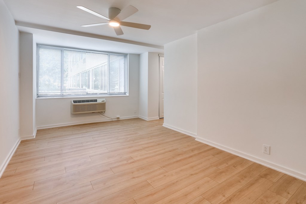 an empty living room with a ceiling fan and a window