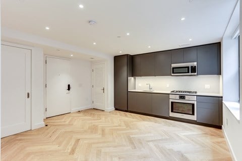 a renovated kitchen with a wooden floor and black cabinets