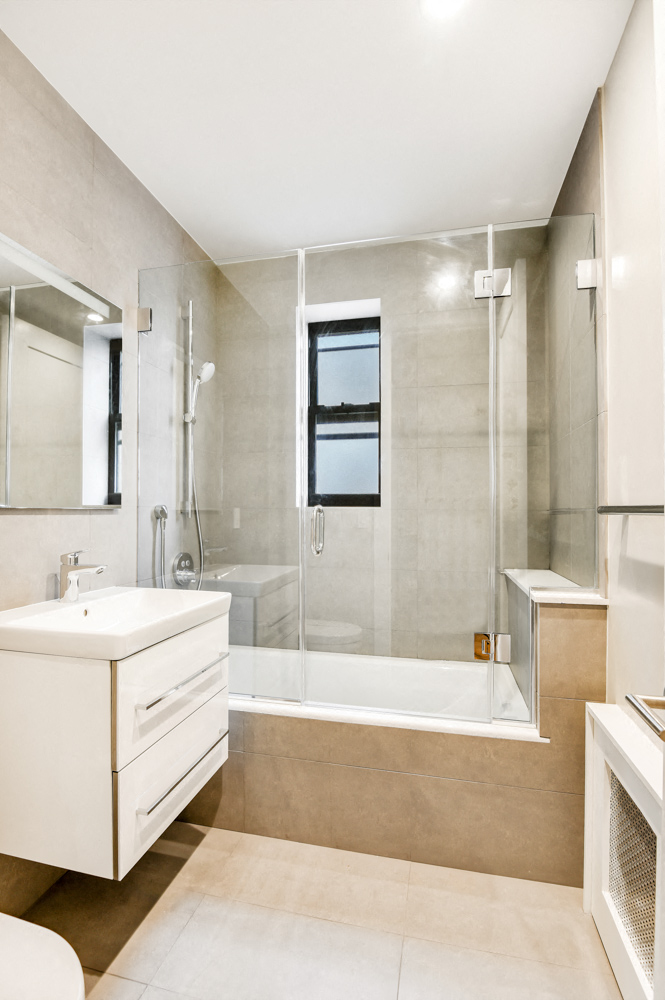 A modern bathroom with a walk-in shower and a white sink vanity.