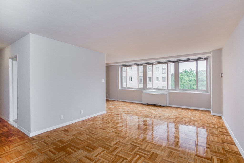 an empty living room with wood flooring and a window