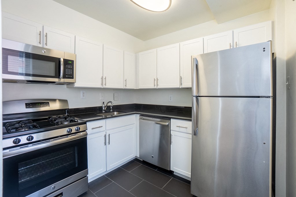 A modern kitchen with a stainless steel refrigerator, microwave, and oven.