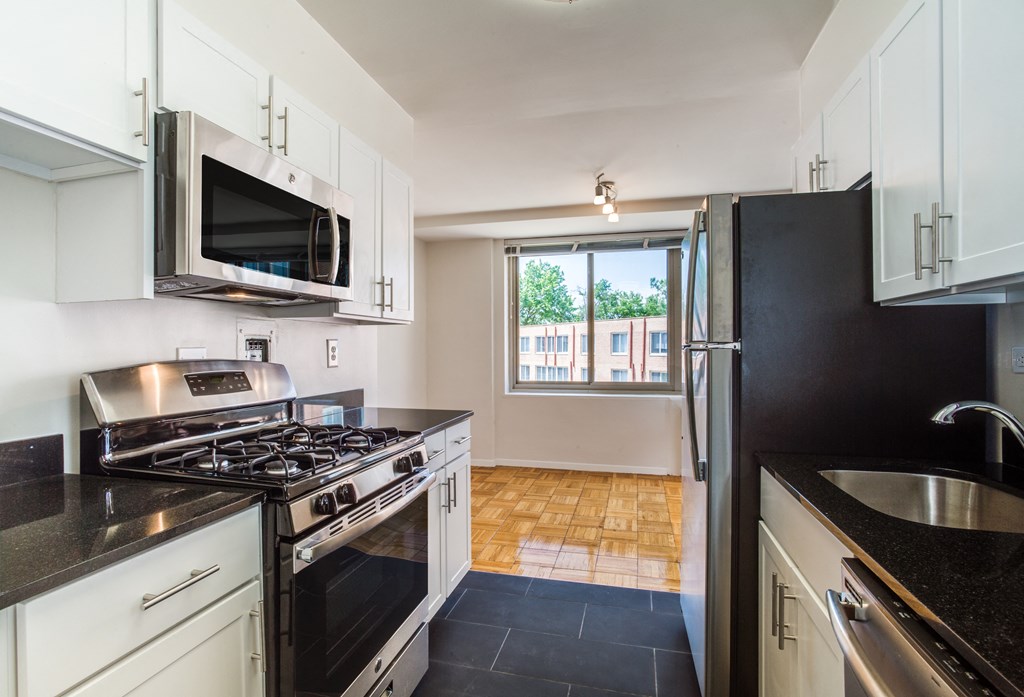 A kitchen with black countertops and white cabinets.