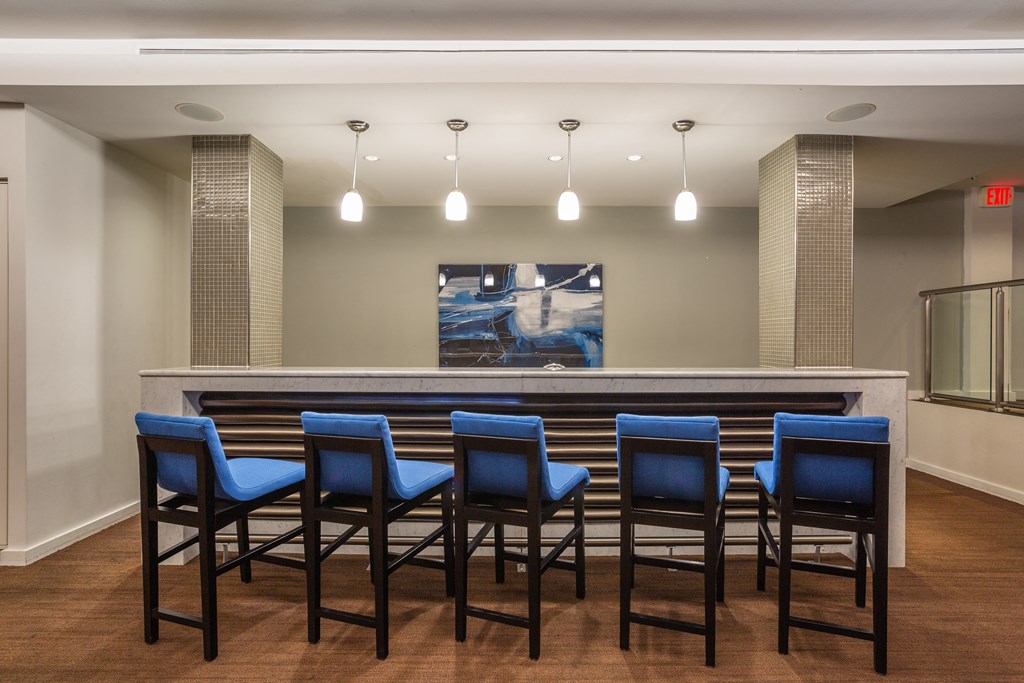A bar with blue chairs and a painting on the wall.