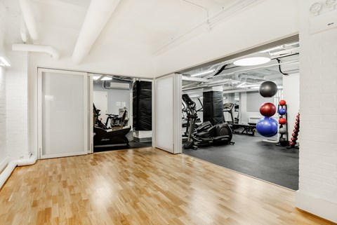 A gym with a mirrored wall and wooden floors.