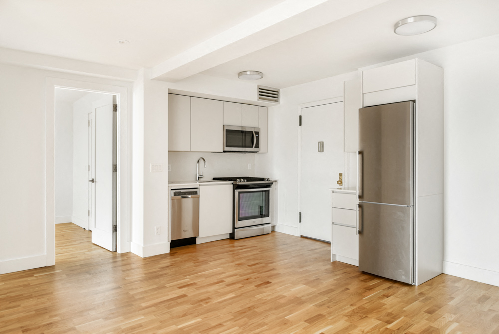 A kitchen with a refrigerator, microwave, oven, and sink.