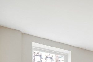 A room with wooden floors and a window showing a building outside.
