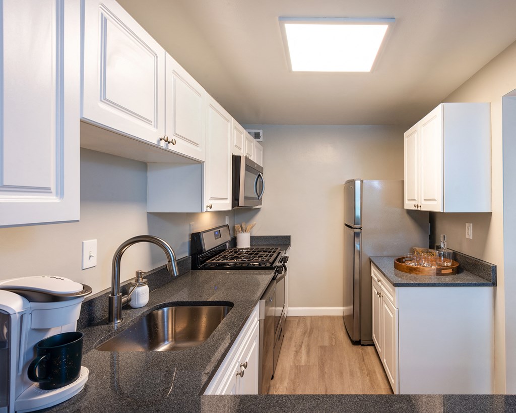 a kitchen with granite counter tops and a stainless steel refrigerator