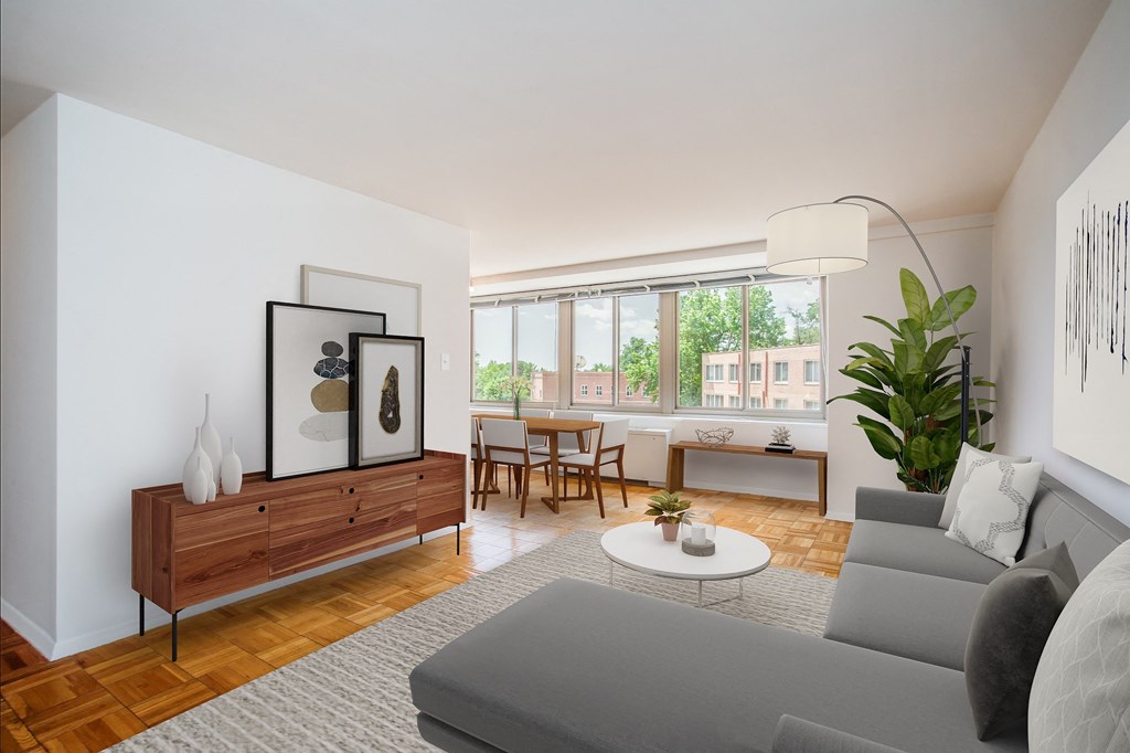 A living room with a grey couch, a wooden cabinet, a coffee table, and a large window.