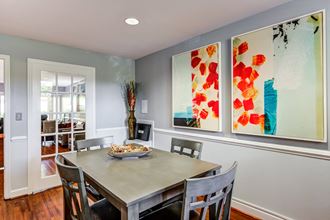a dining room with a table and chairs and two paintings on the wall