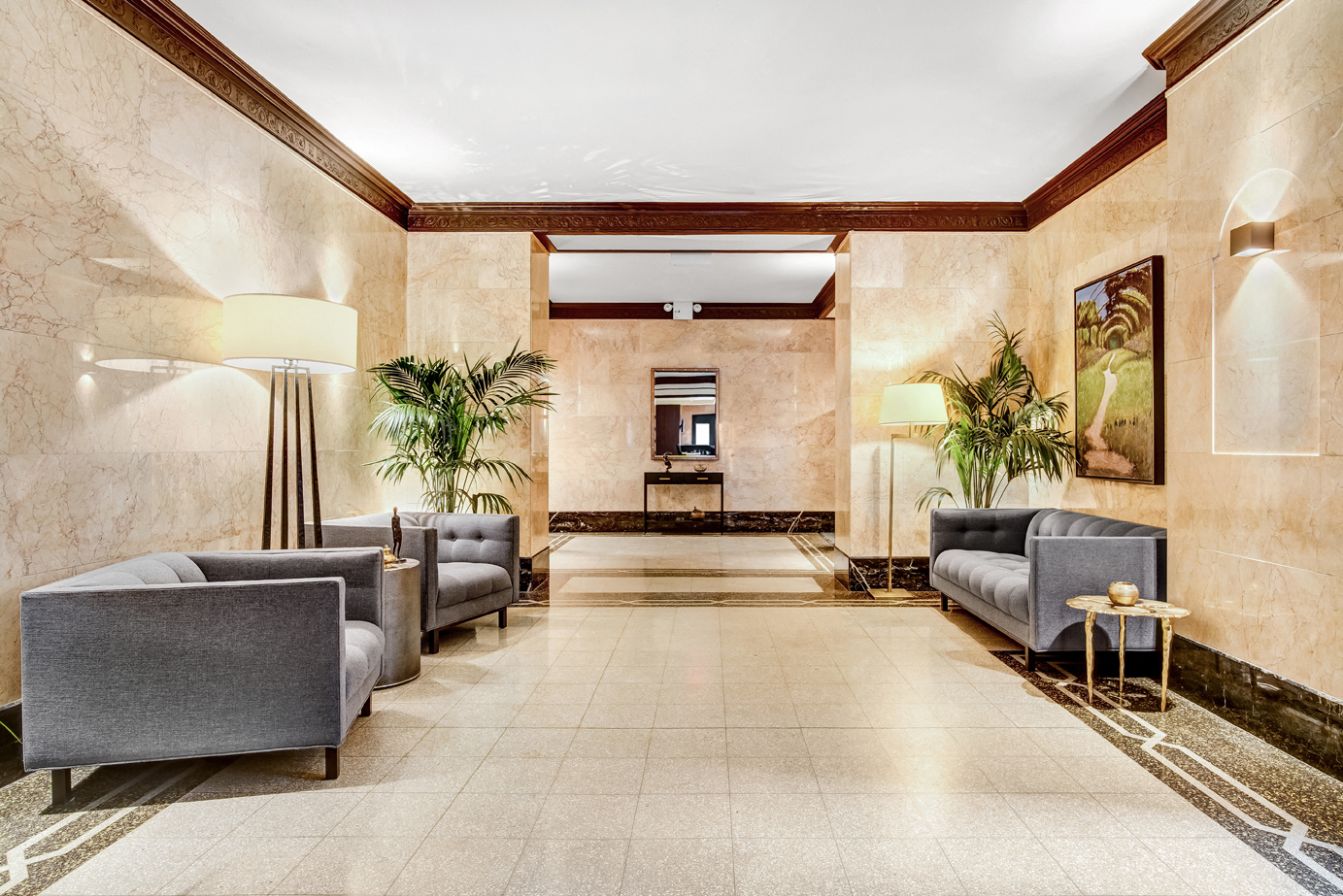 A spacious waiting area with grey couches and plants.
