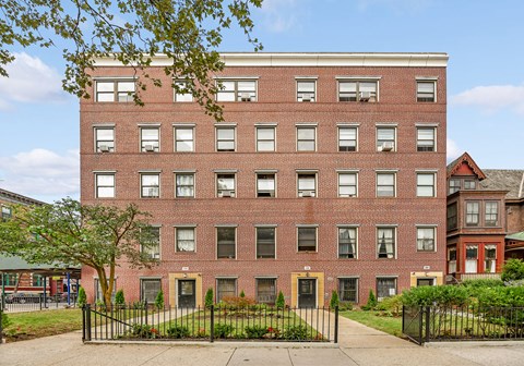 A red brick building with a black fence in front.