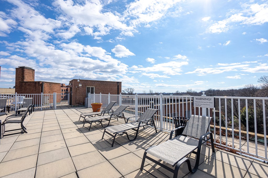 A sunny day on a balcony with chairs and a warning sign.