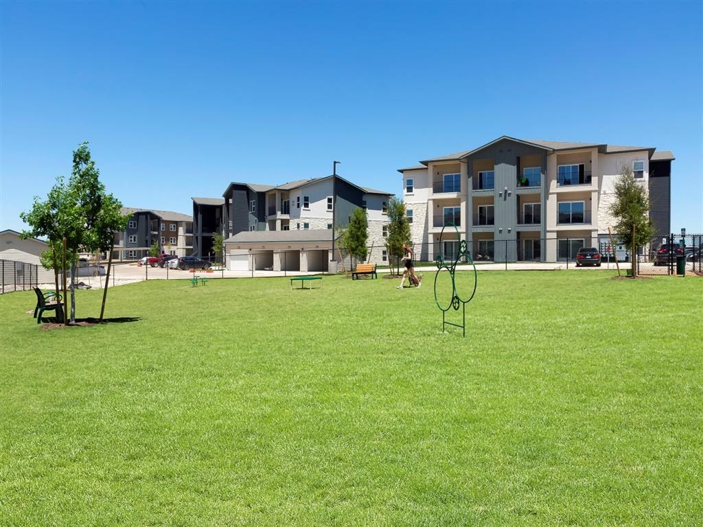 a park with a swing set in front of some apartments