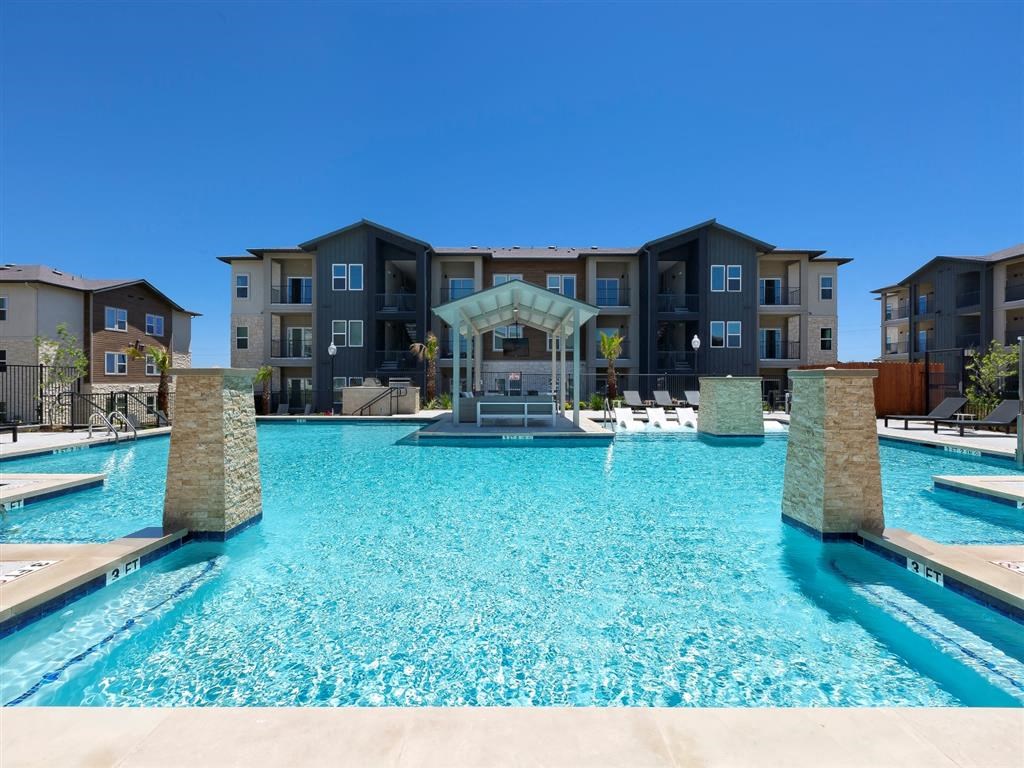 a large swimming pool with apartments in the background